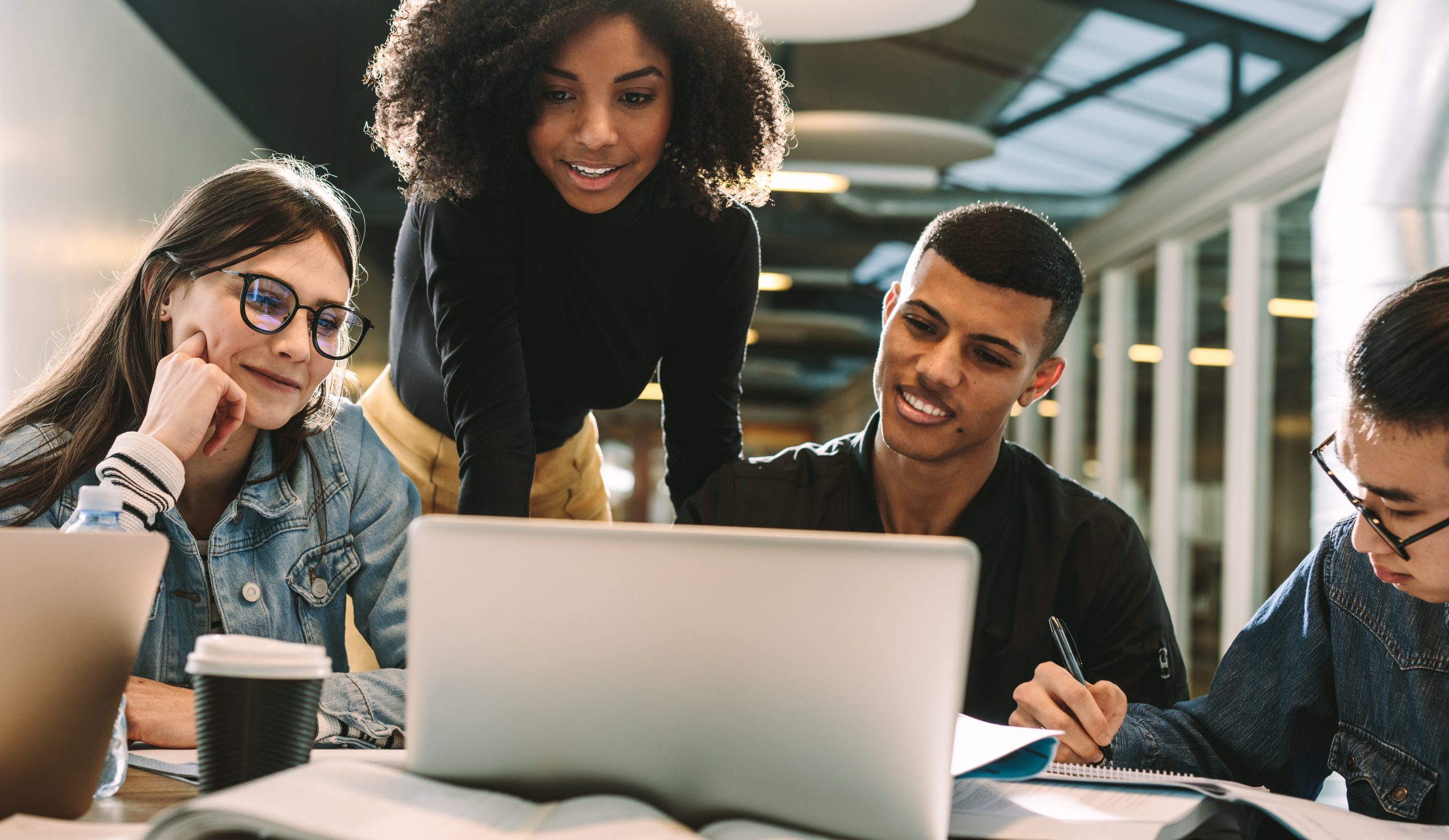 Four students using laptop for research at library